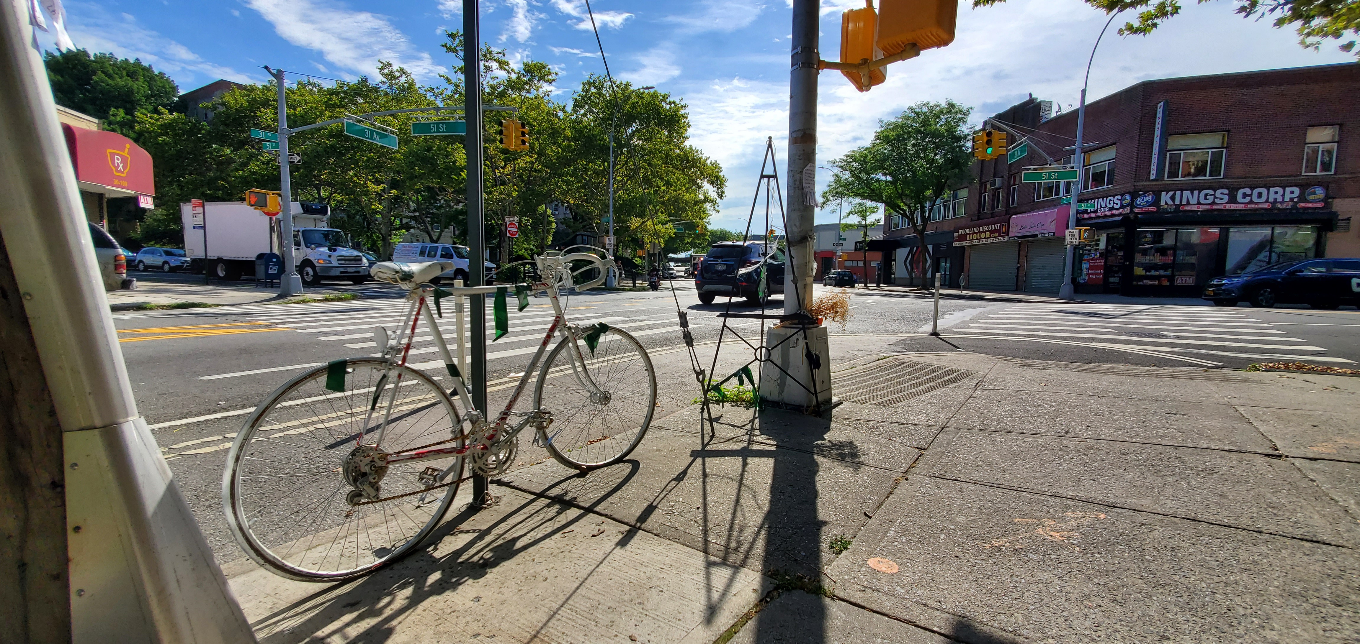 White bike chained to street sign near intersection